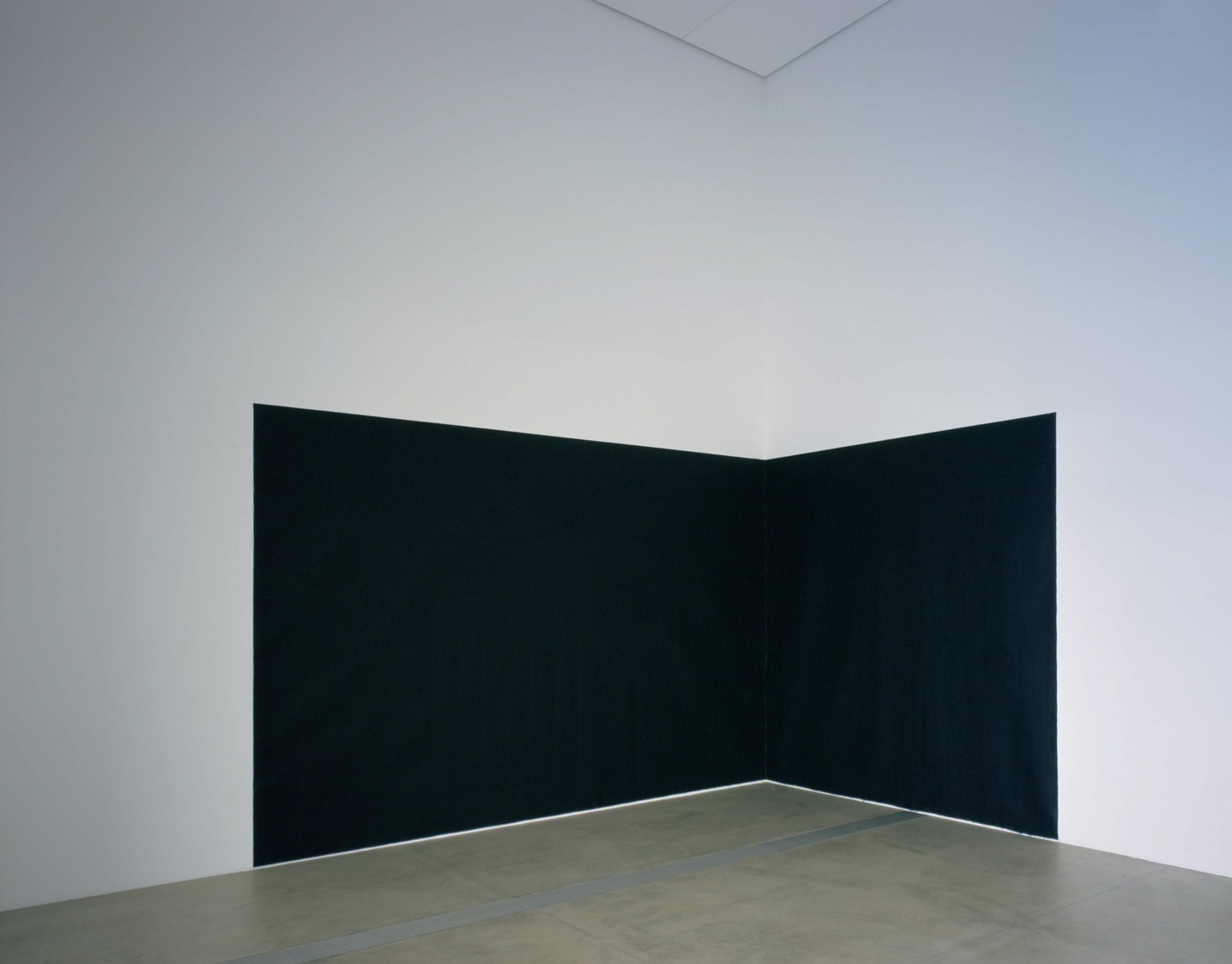 A large black rectangular piece that runs across one wall to another in a corner in the Cube Gallery.