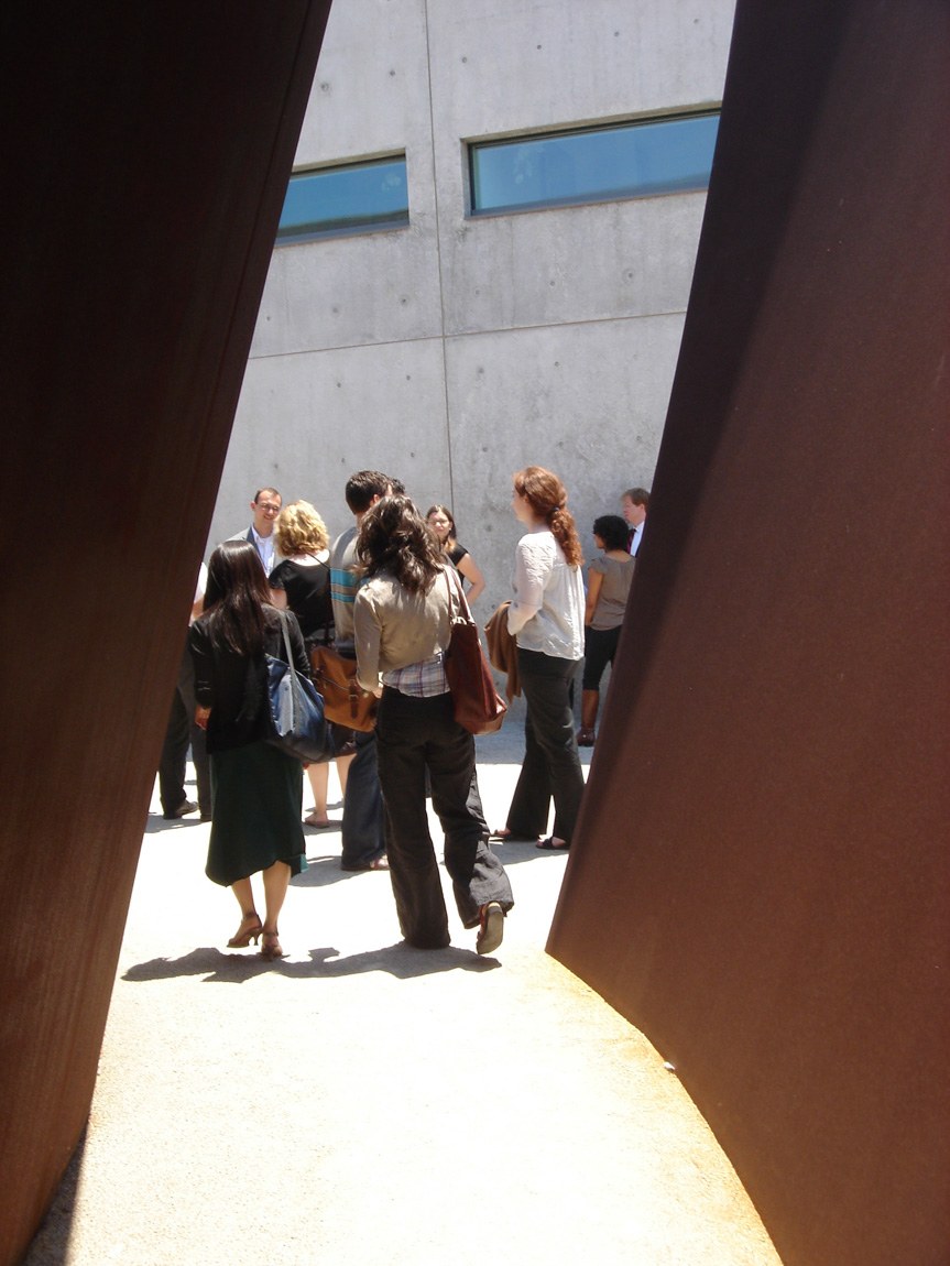 A view from within the piece: visitors gathering outside "Joe" by Richard Serra on a sunny day.