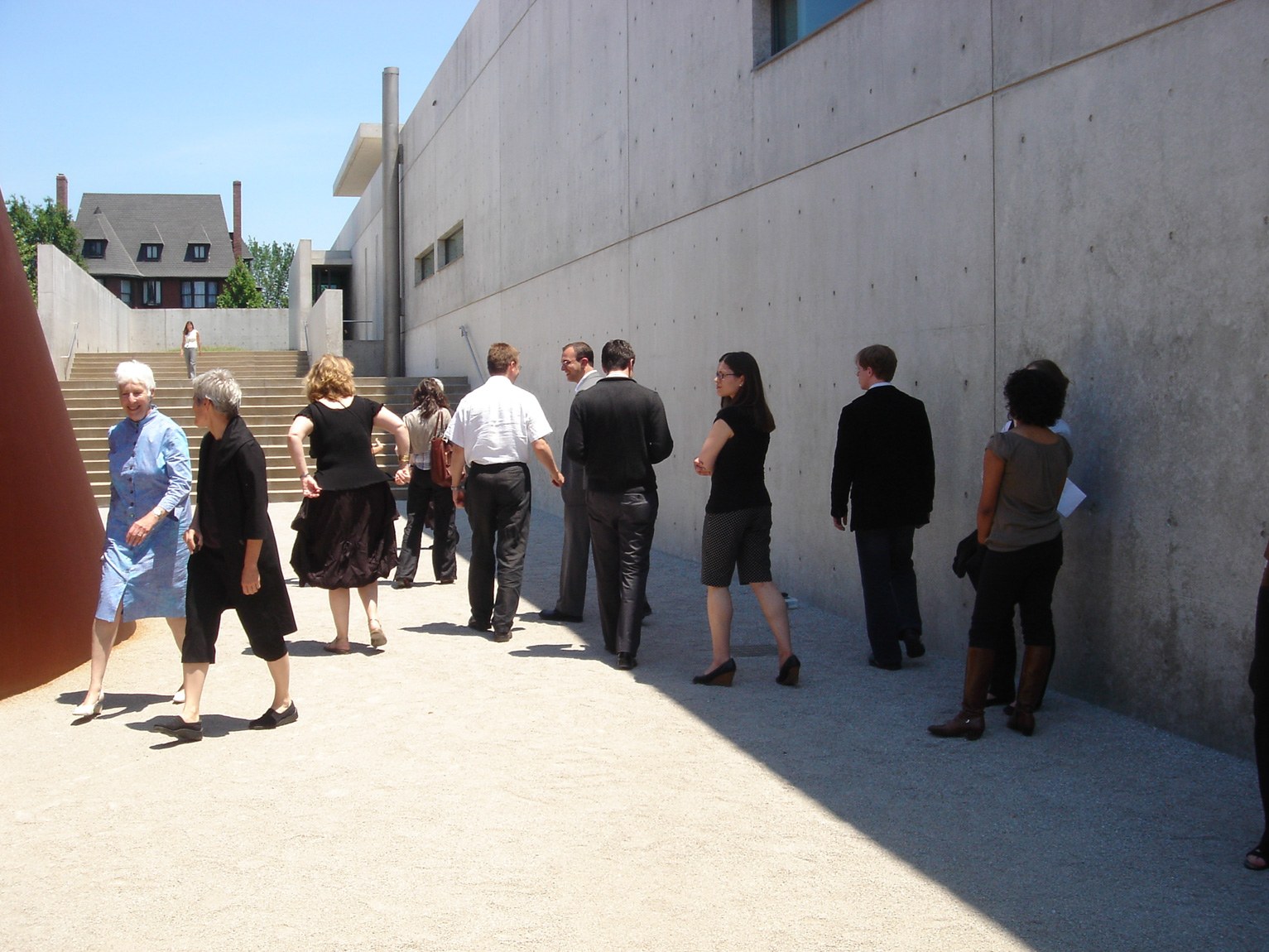 Visitors and staff gather near Serra's "Joe" on a sunny day.
