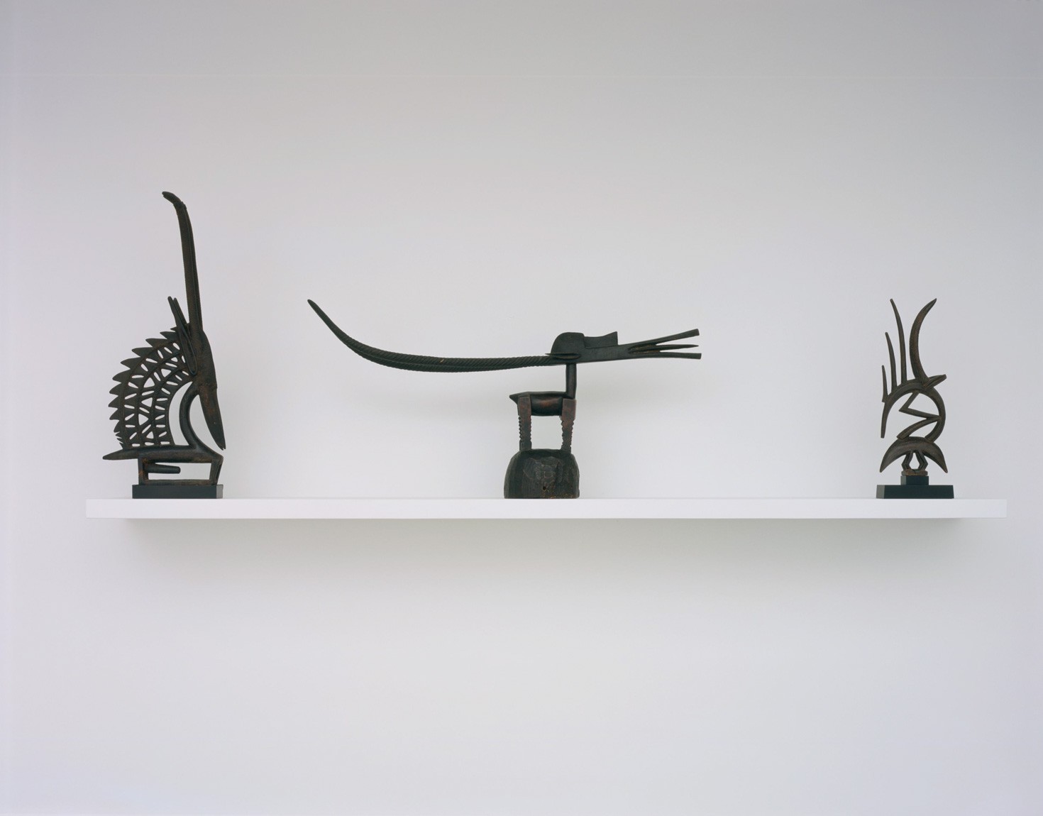 Three sculptures sit on a white shelf in the Lower Galleries.