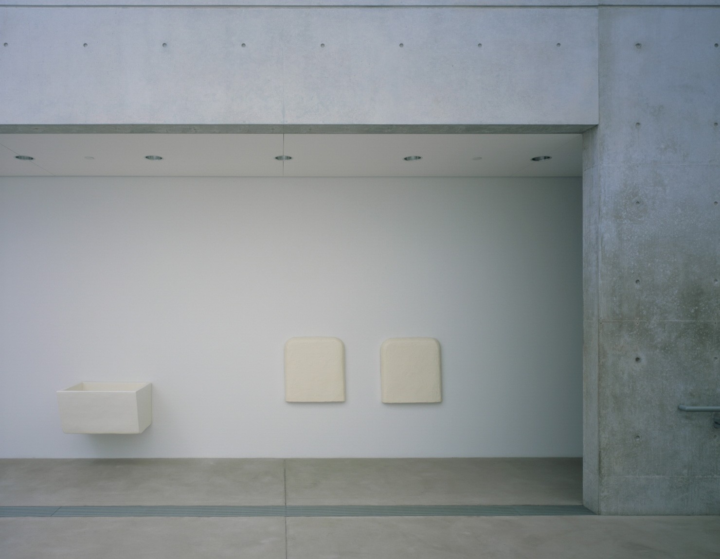 A white hollow box is installed on a wall in the Lower-Main Gallery. Two white squares hang on the wall beside it.