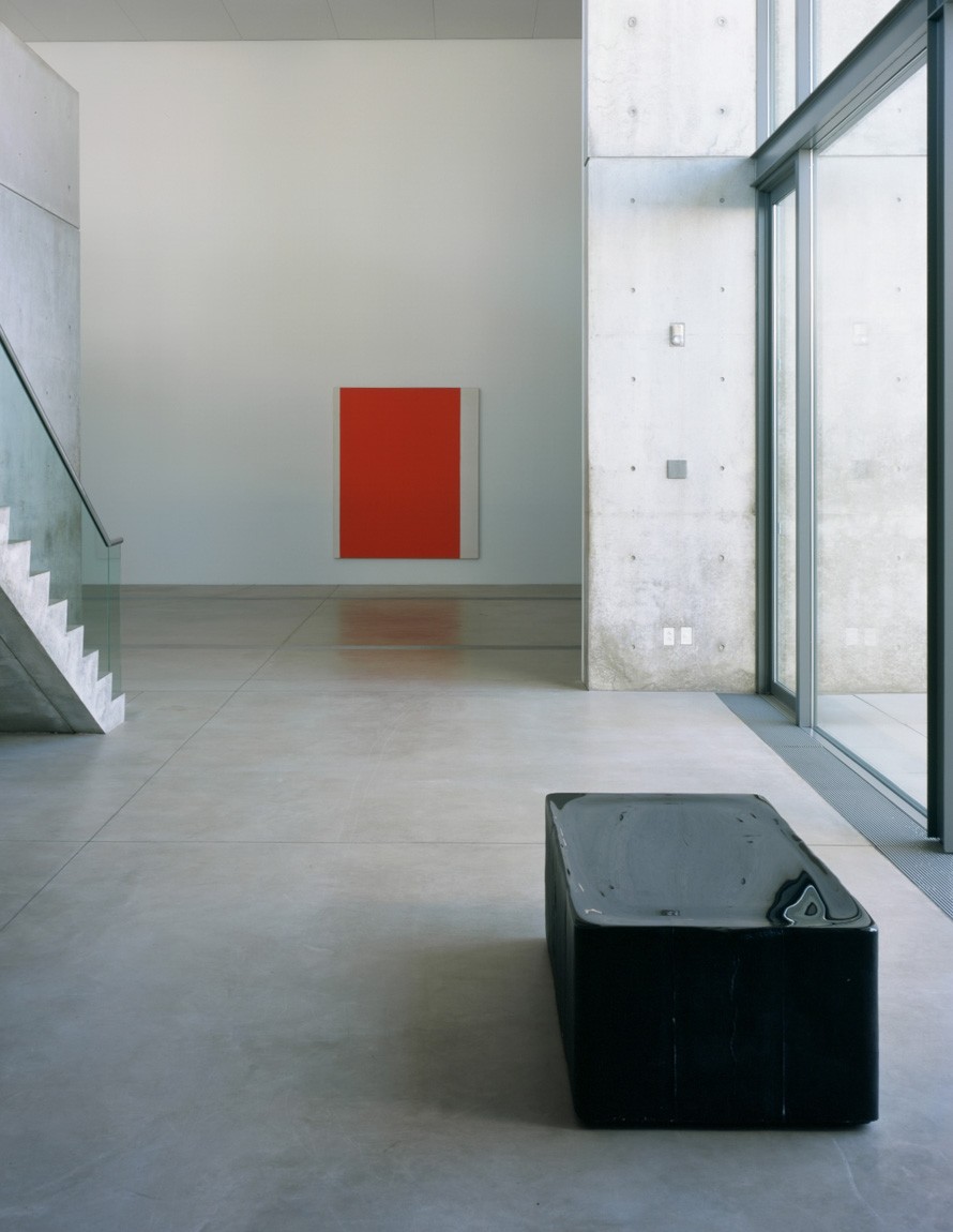 A glossy black rectangular block sits on the floor before the Water Court windows, with a view of an orange piece by Kelly in the Main Gallery.