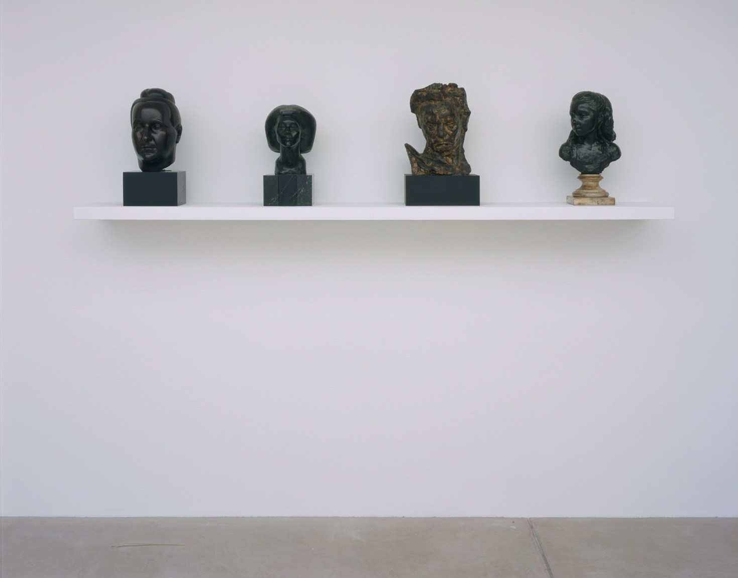 Four busts of varying styles sit on a white wall shelf in the Lower-Main Gallery.