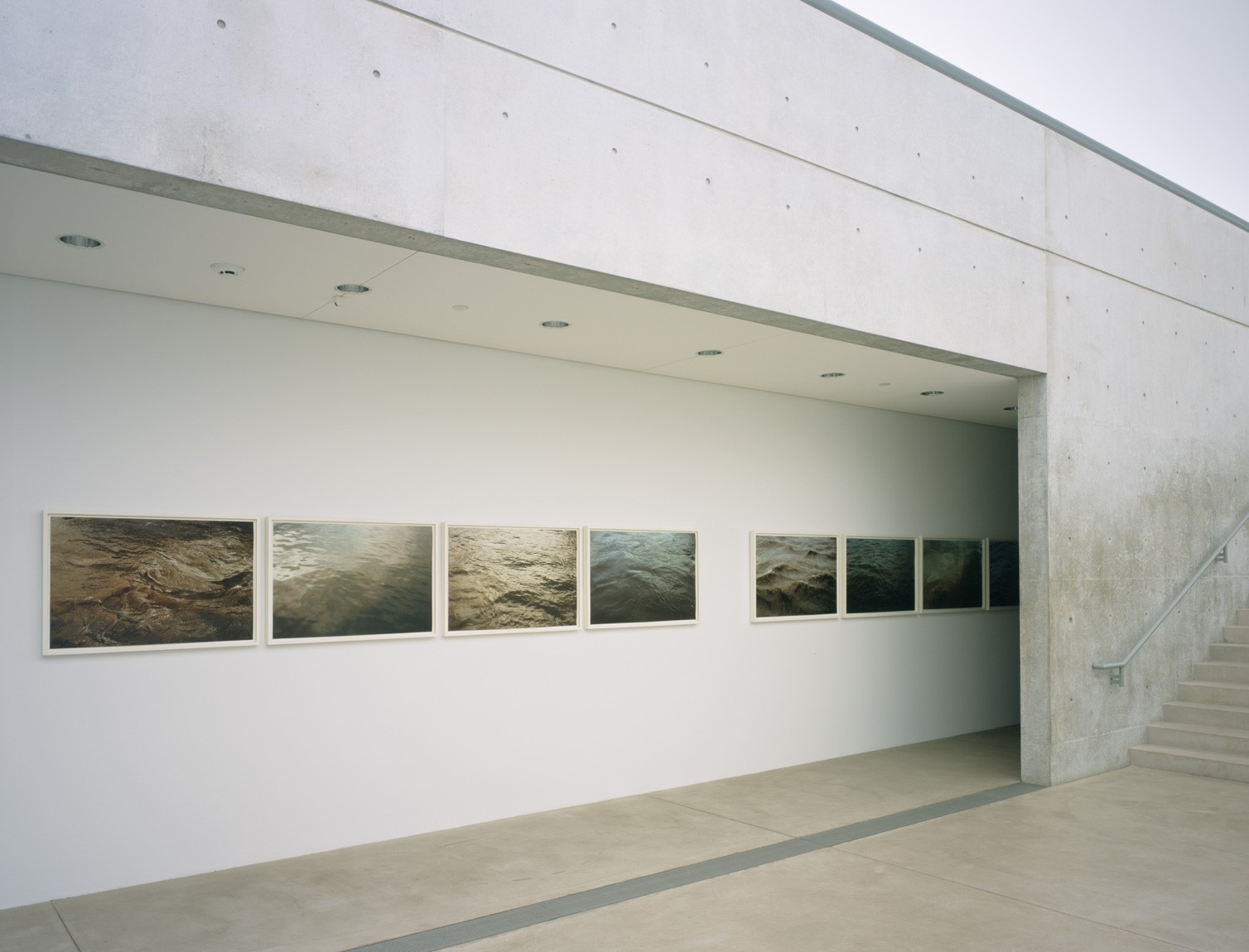 Roni Horn's series of water scene photographs of the Thames titled "Some Thames - Group J" and "Some Thames - Group E" are displayed in a row on the Lower Corridor wall.