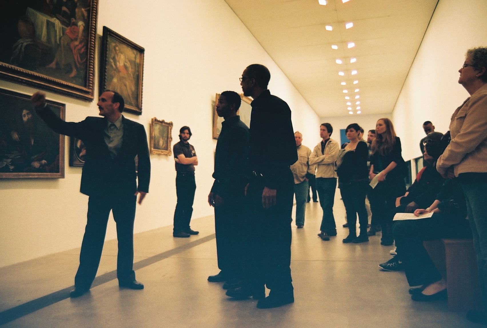 A tour guide discusses the paintings with a crowd of guests in the Main Gallery.