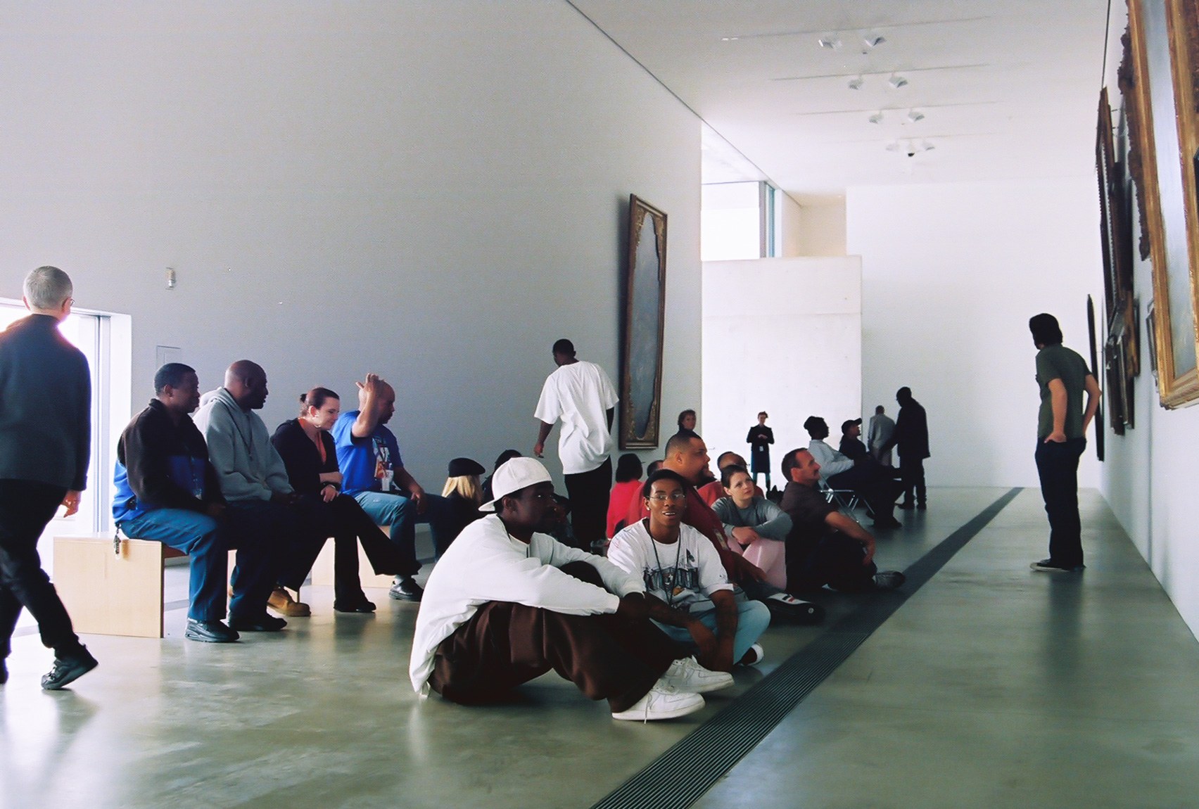 A crowd sits in the Main Gallery, facing a wall of paintings.