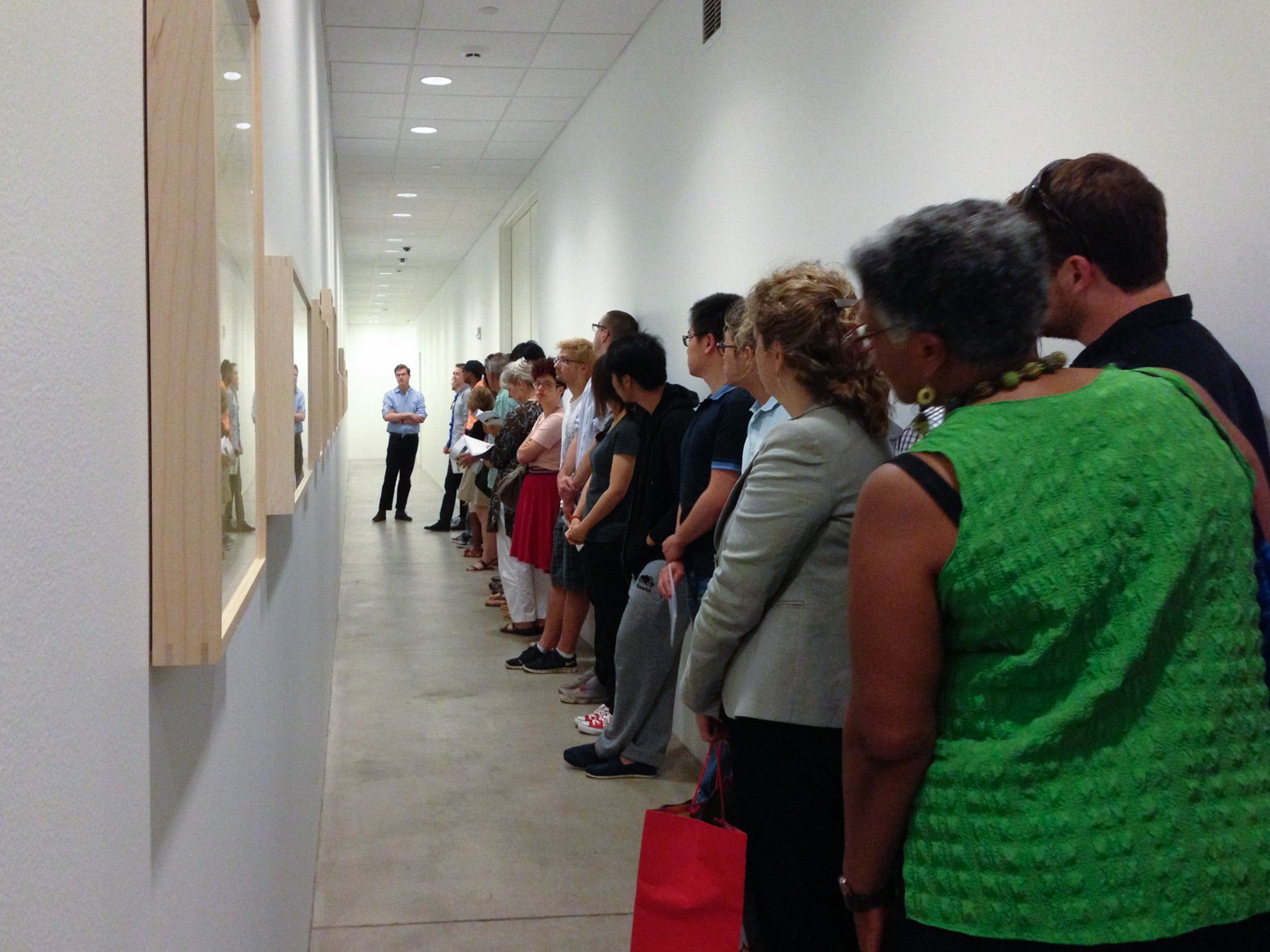 Participants line the lower-level hallway and listen to an individual speak at the far end.