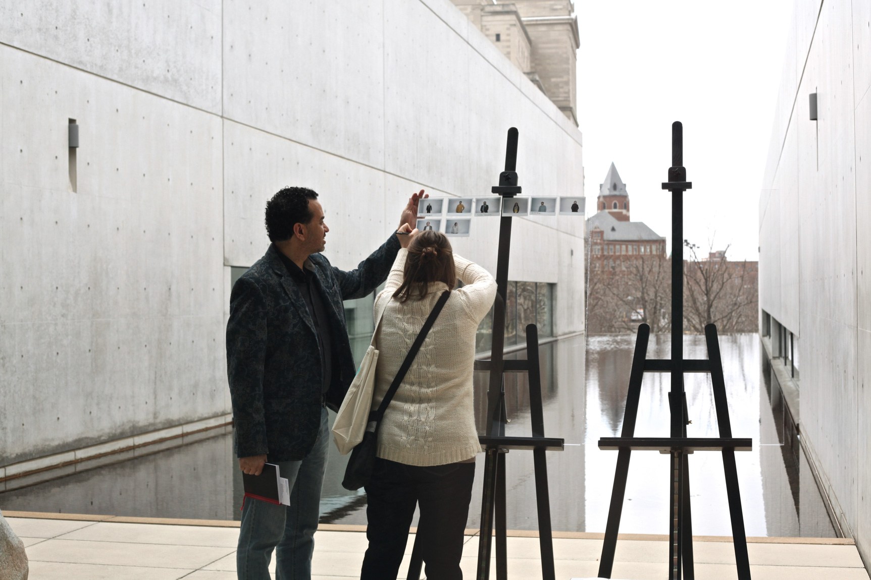 Two visitors remove Polaroids gridded on clear acrylic sheets placed on easels in the Water Court.