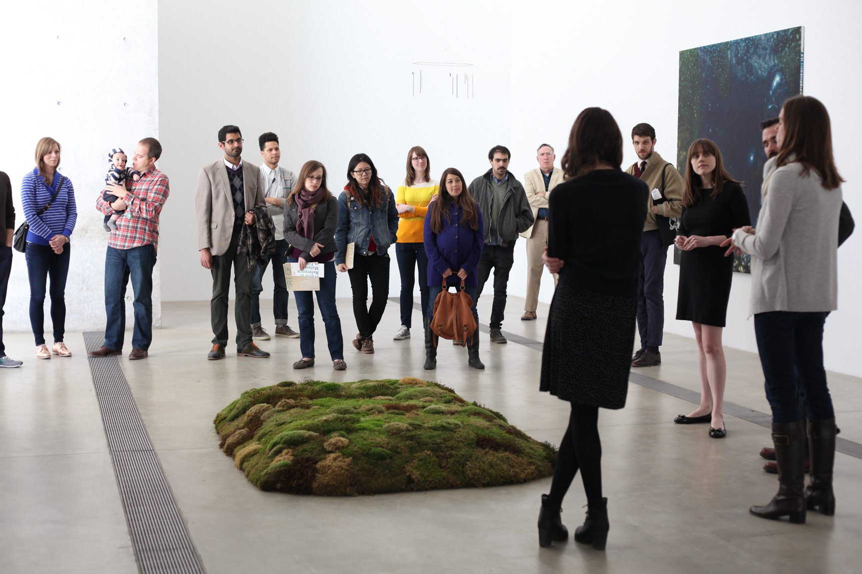 Event facilitators speak to participants in the Main Gallery, gathered around Meg Webster's piece "Moss Bed, Queen."