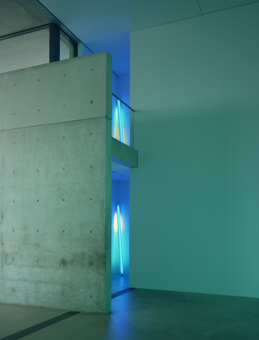 Two blue fluorescent pieces by Flavin titled "untitled (fondly, to Helen)." They sit on separate floors, one above the other, near the elevator doors of the Main Gallery and the Mezzanine.