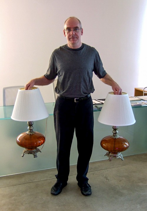 A Lamp Project donor holds their orange vintage lamps by their lampshades.