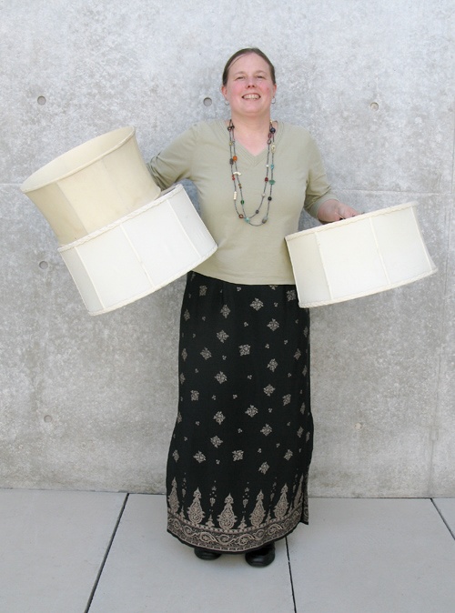 A Lamp Project donor smiles with their three white lampshades.