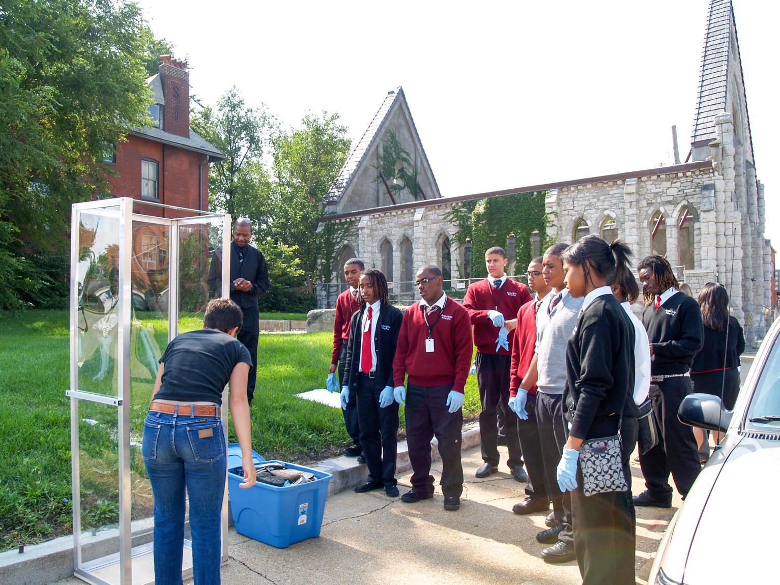 Students from Cardinal Ritter College Prep stand outside the Spring Church and watch the curator speak in front of the garbage glass case.