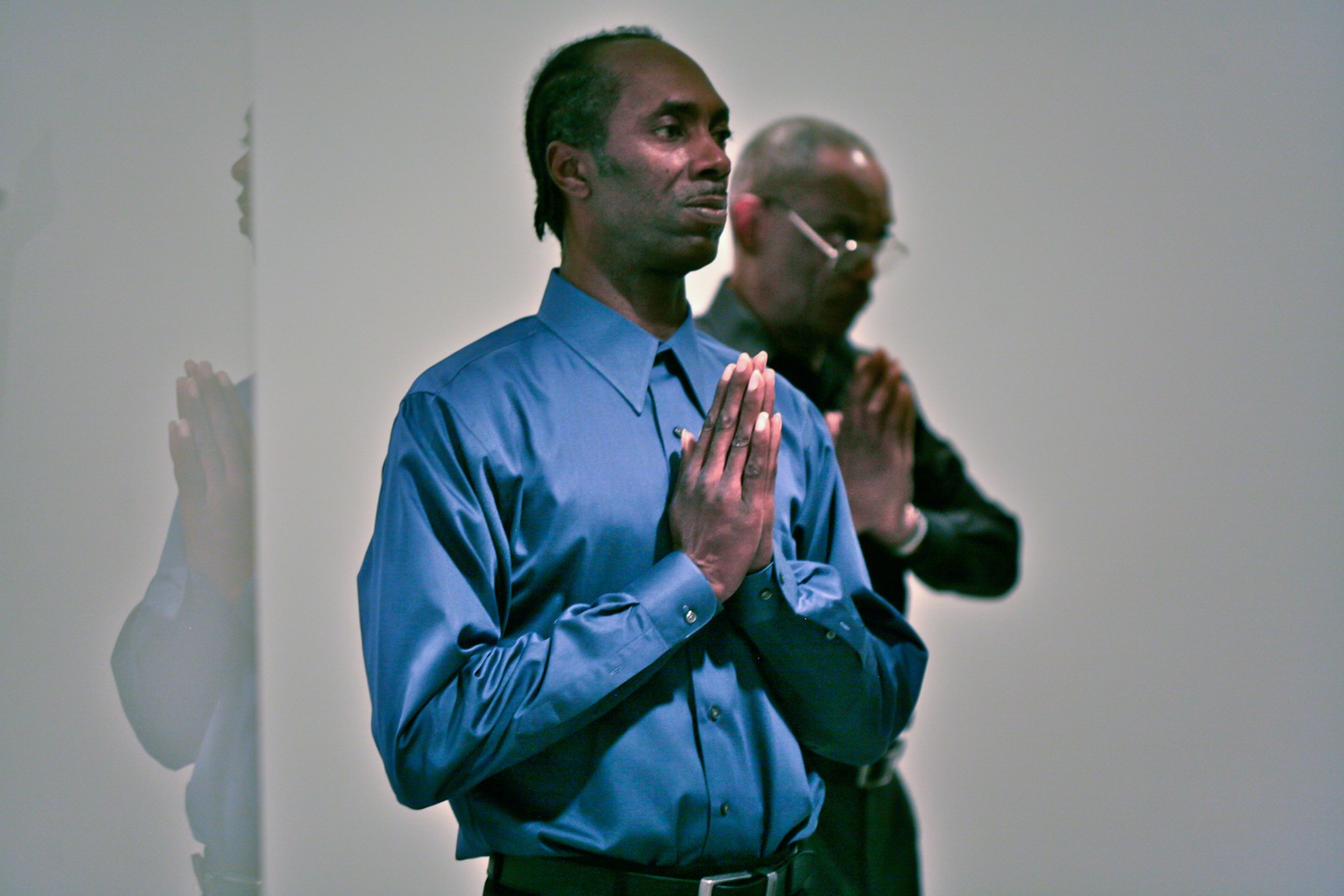 Two participants hold their hands in a praying pose.