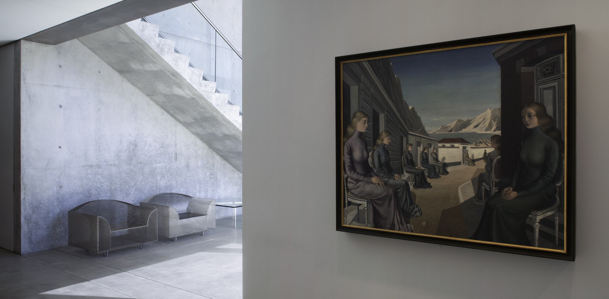 View of Paul Delvaux's "Village of the Mermaids" in the Entrance Gallery. The painting depicts women sitting in a row leading to a mountain seaside view.