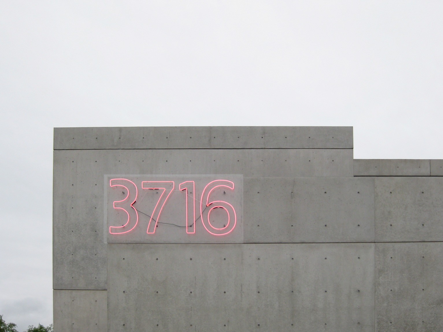 A view of a pink neon sign outlining "3716" installed on the side of the Pulitzer.