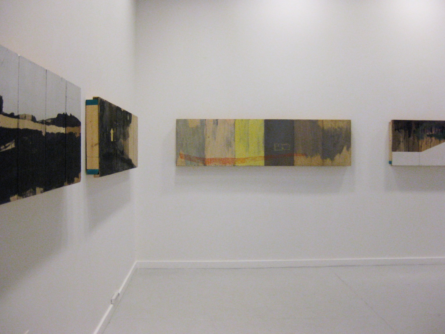 An photo of four works on board, mounted to a gallery wall.