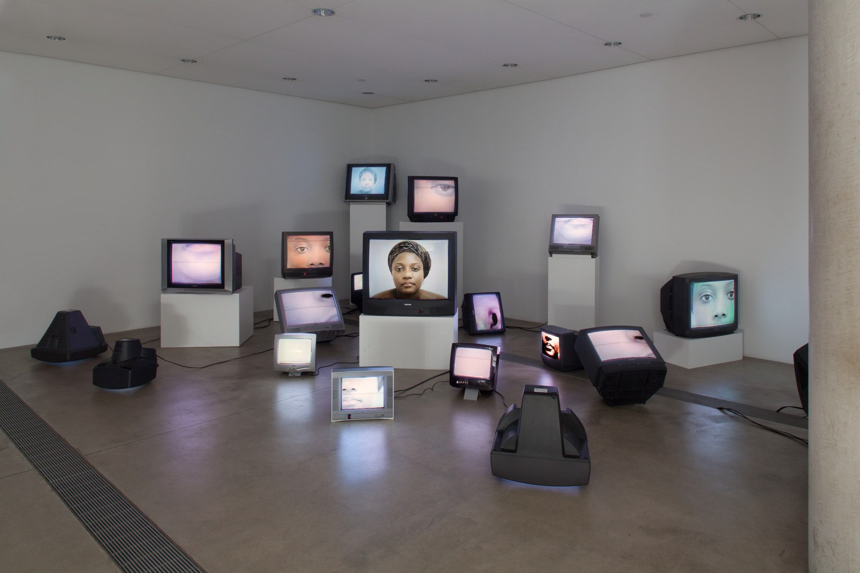 An exhibition view of Nina Saro-Wiwa's "Mourning Class: Nollywood," an installation made up of TV screens and monitors displaying images of the artist's face.