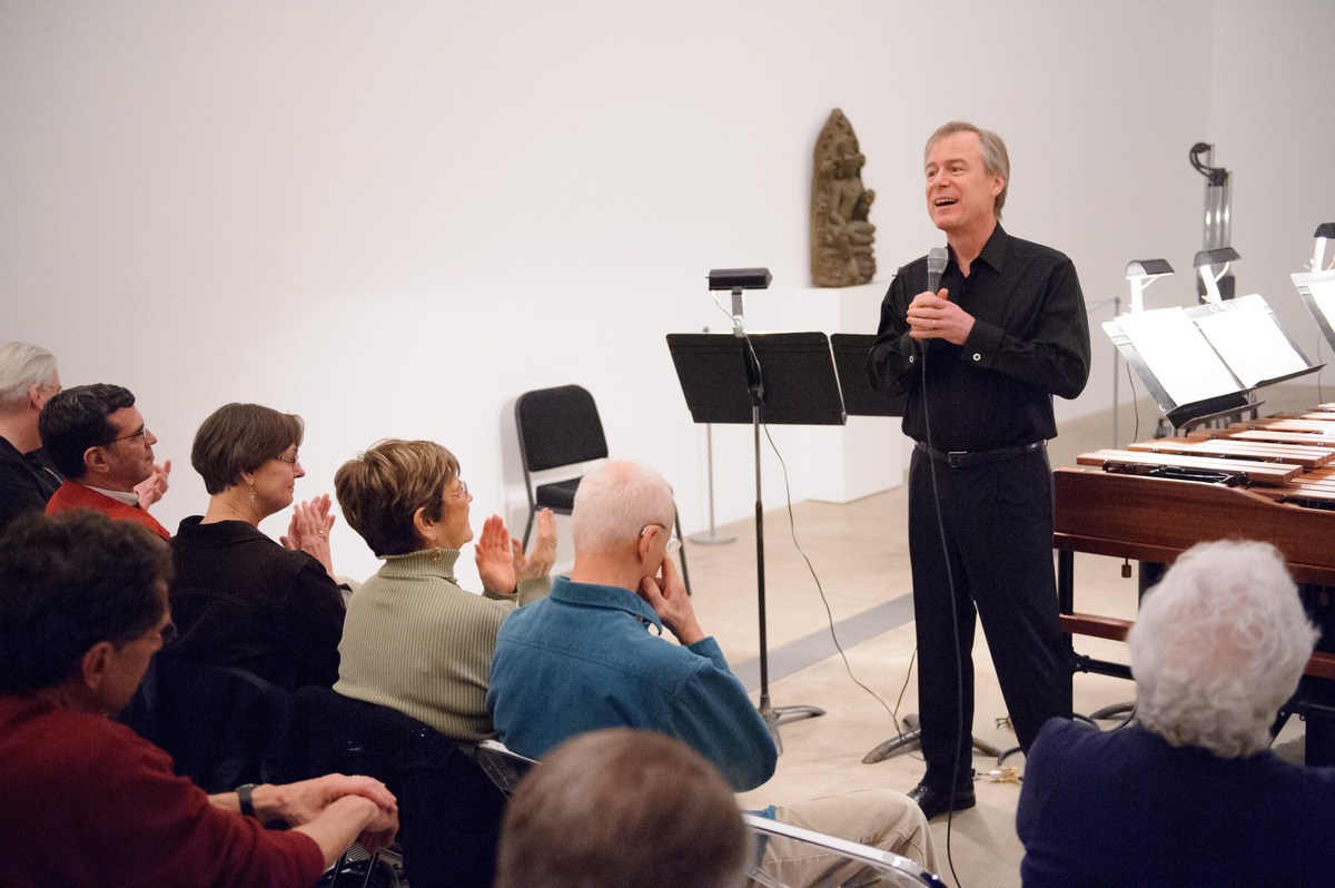 David Robertson speaks into a microphone to the audience in the Lower-Main Gallery.