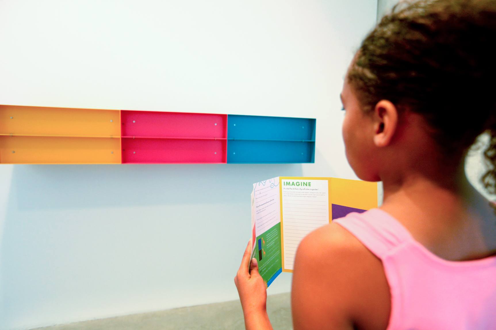 A young visitor views a Donald Judd piece while holding an activity guide.