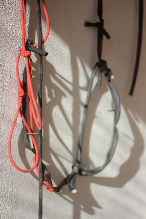 A closeup of red and black thin rubber strands tied together and nailed in place on a wall.