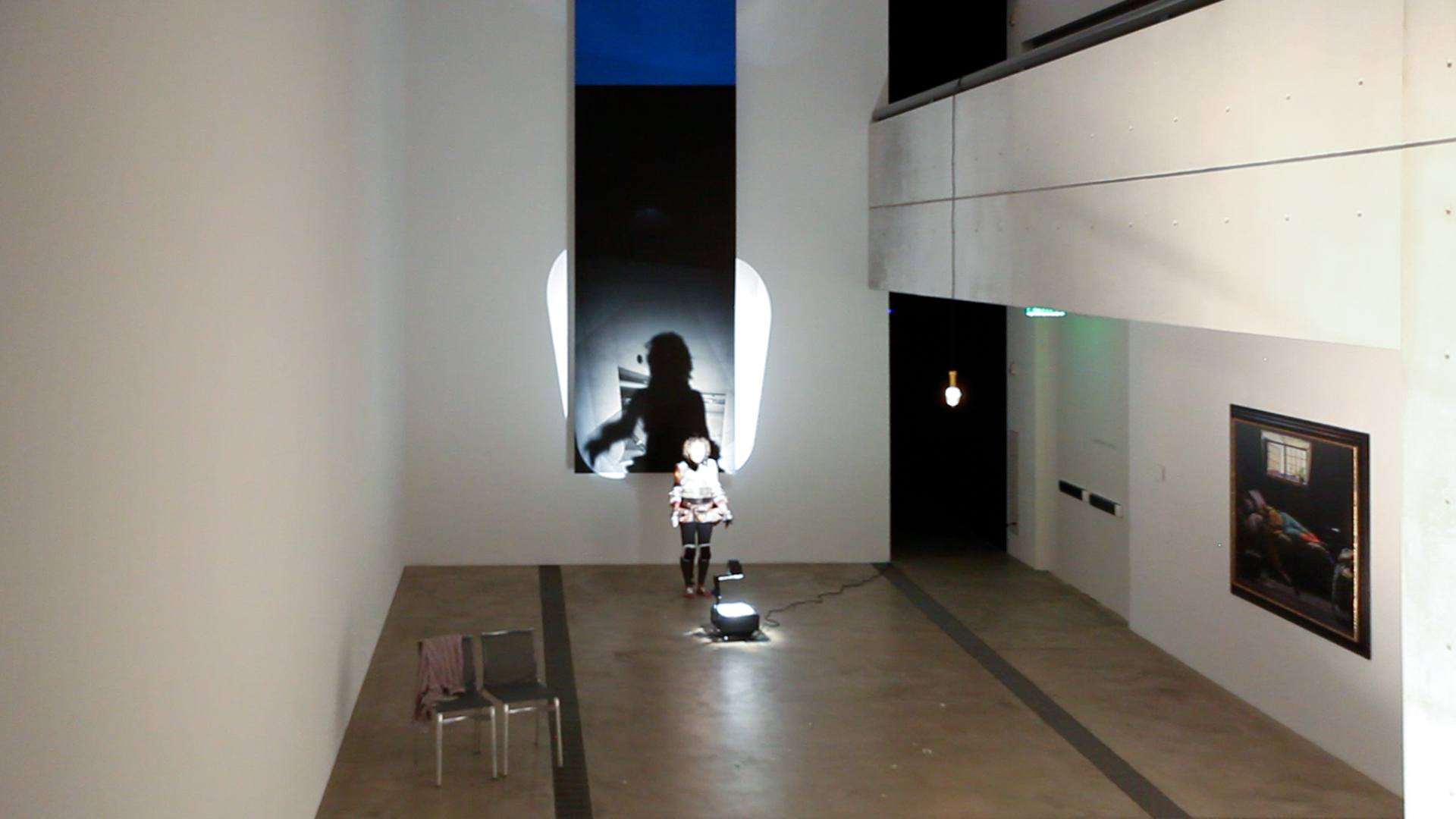 Wura-Natasha performs with an overhead projector on the floor shining a light on her and projecting a shadow onto “Blue Black” by Ellsworth Kelly.