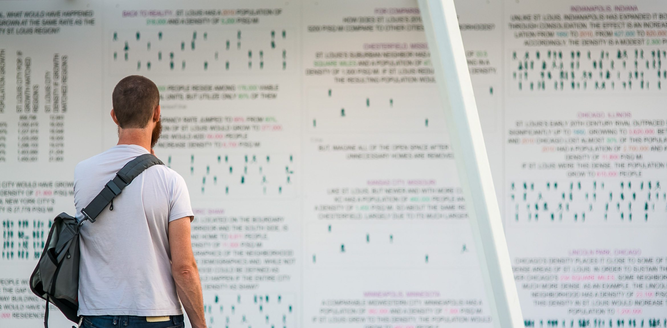 A visitor stands before a wall of diagrams under the Lots installation.