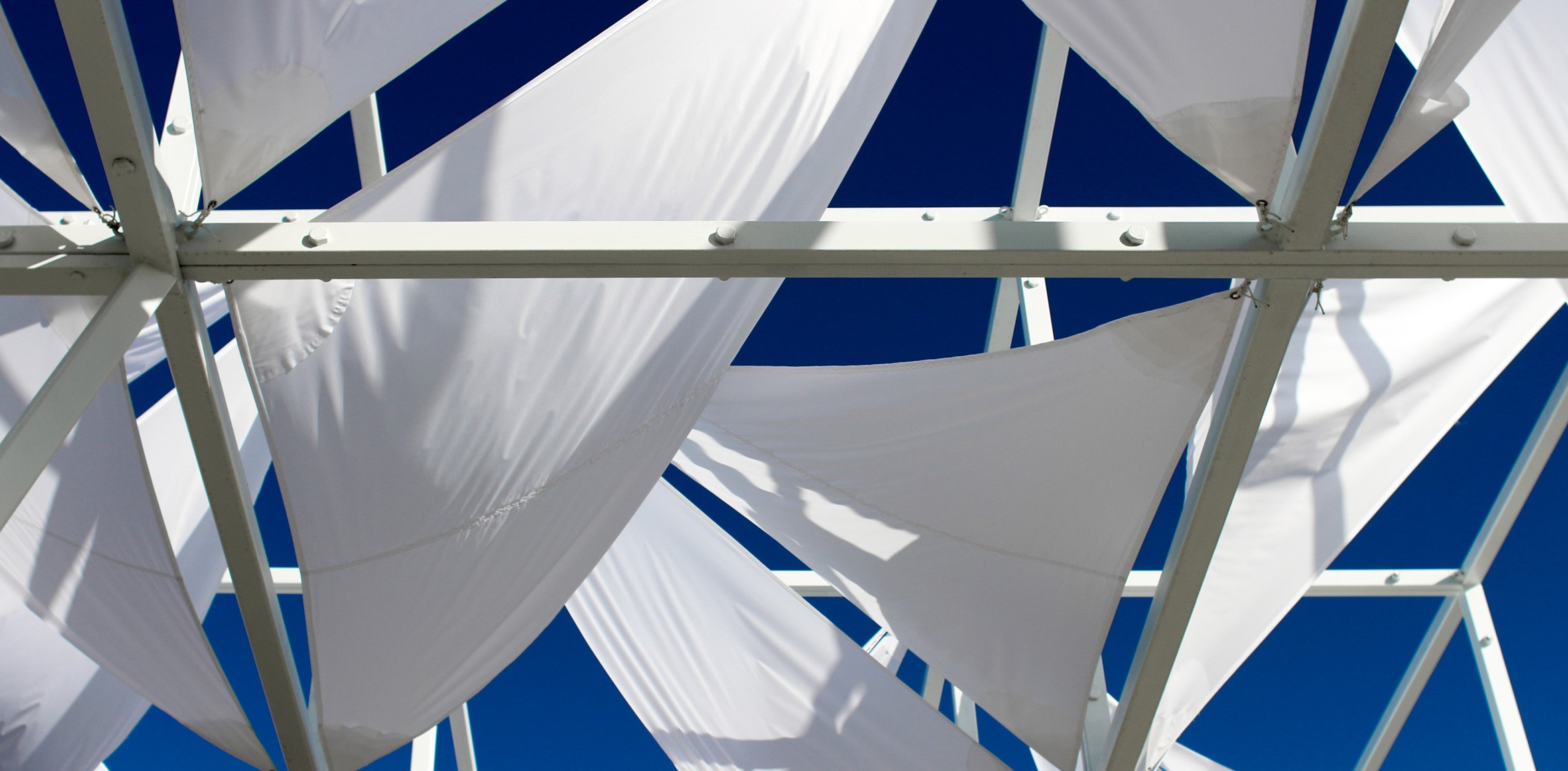 A view of the Lots installation white canpoy fabric pieces against a blue sky.