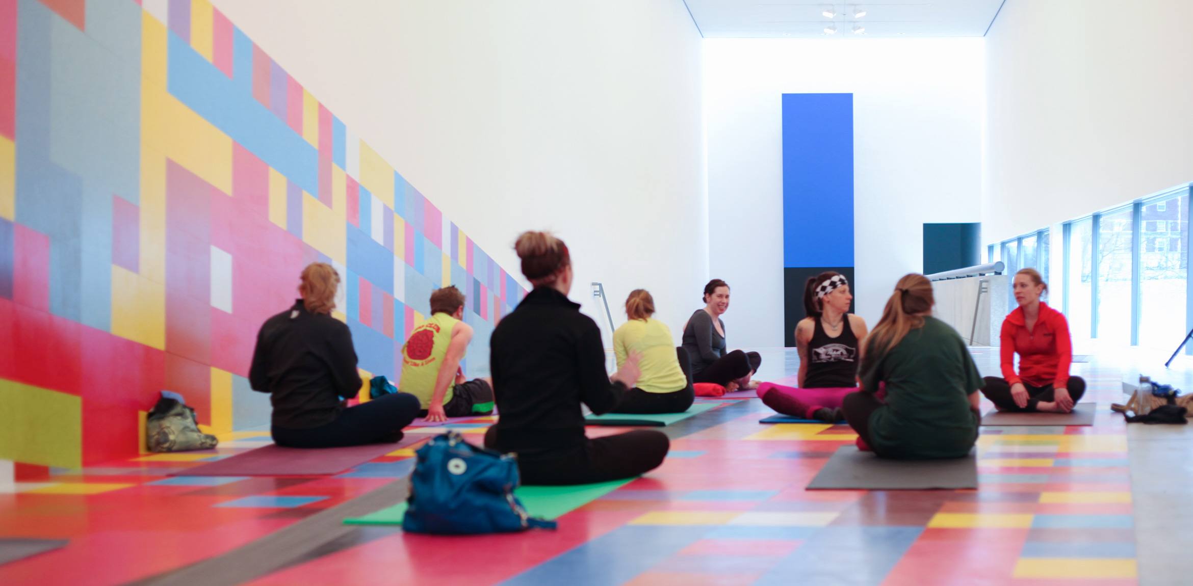 Yoga participants sit on yoga mats in the Main Gallery to talk before the event begins.
