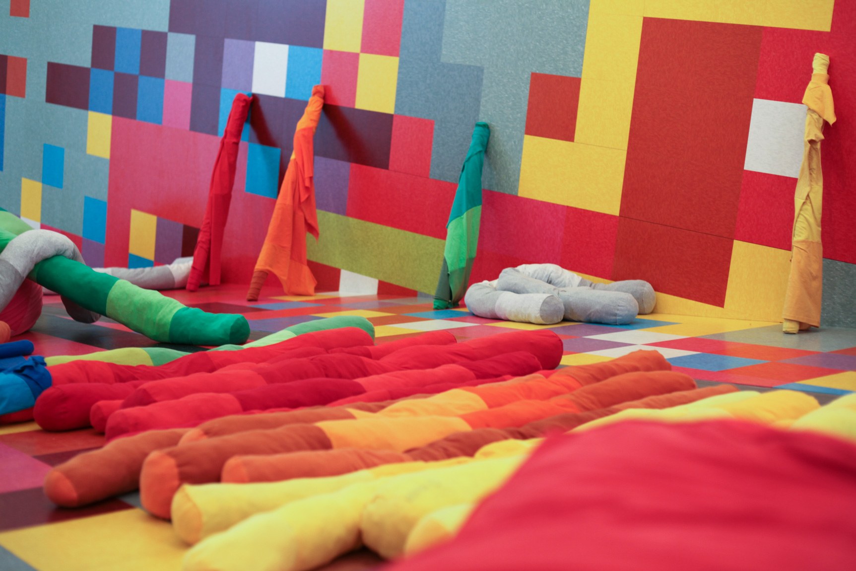 Long, thin colorful pillows lie on the floor of David Scanavino's installation "Candy Crush."