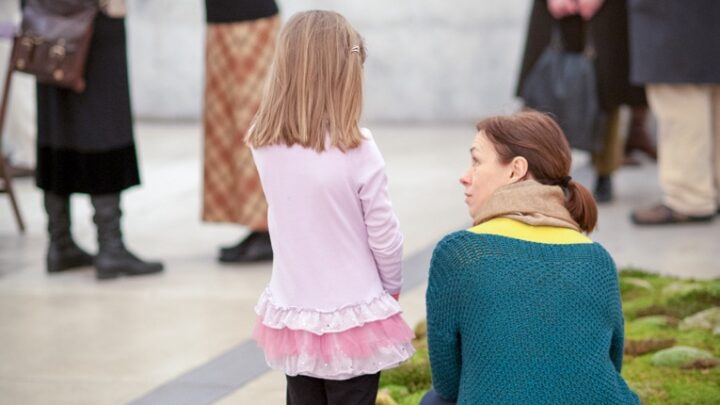 A parent and child observe a mossy installation piece placed on the ground in the Main Gallery.