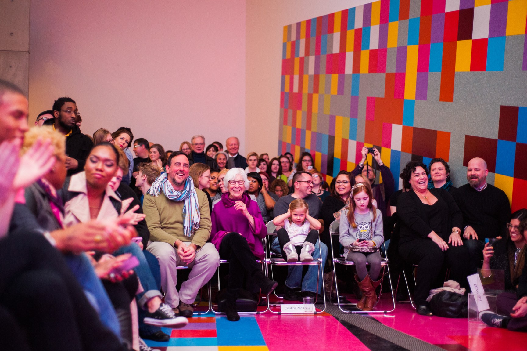A packed audience in the Main Gallery attends the drag performance, with David Scanavino's installation "Candy Crush" next to them.