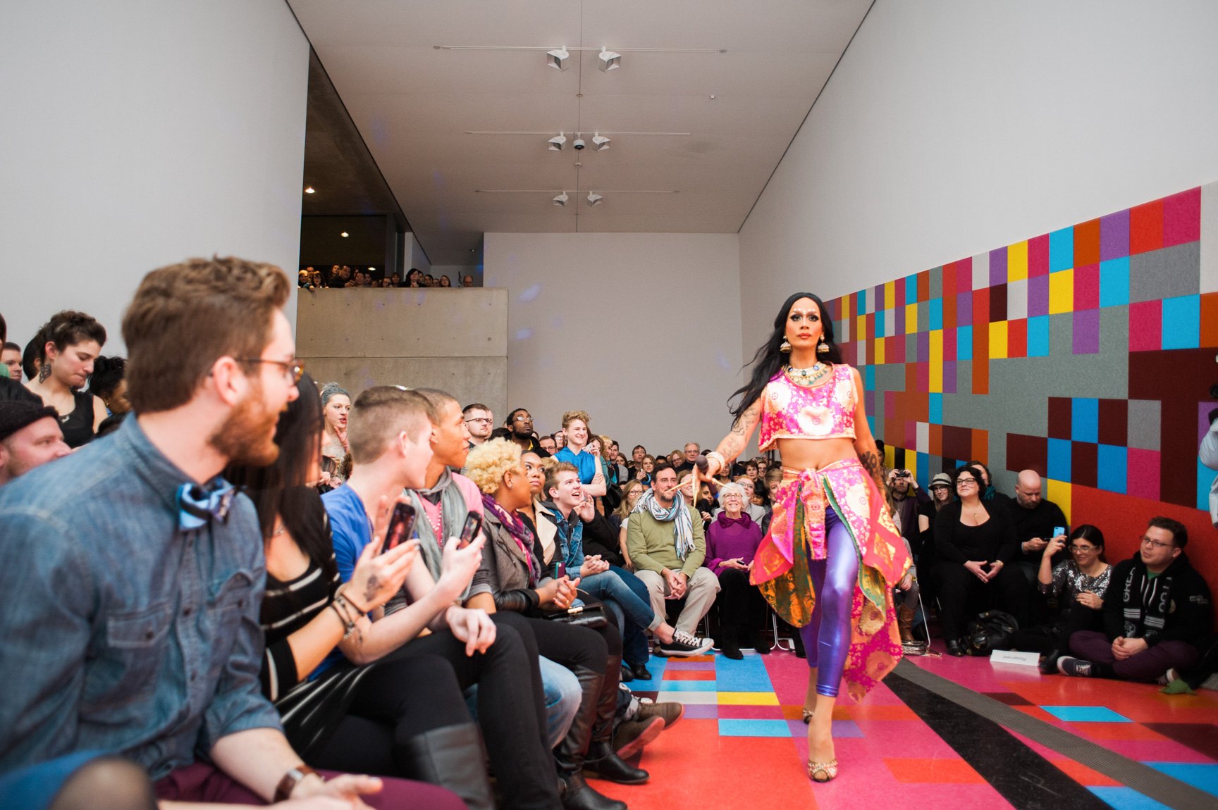 A drag performer struts in the Main Gallery for a packed audience in front of David Scanavino's installation "Candy Crush."
