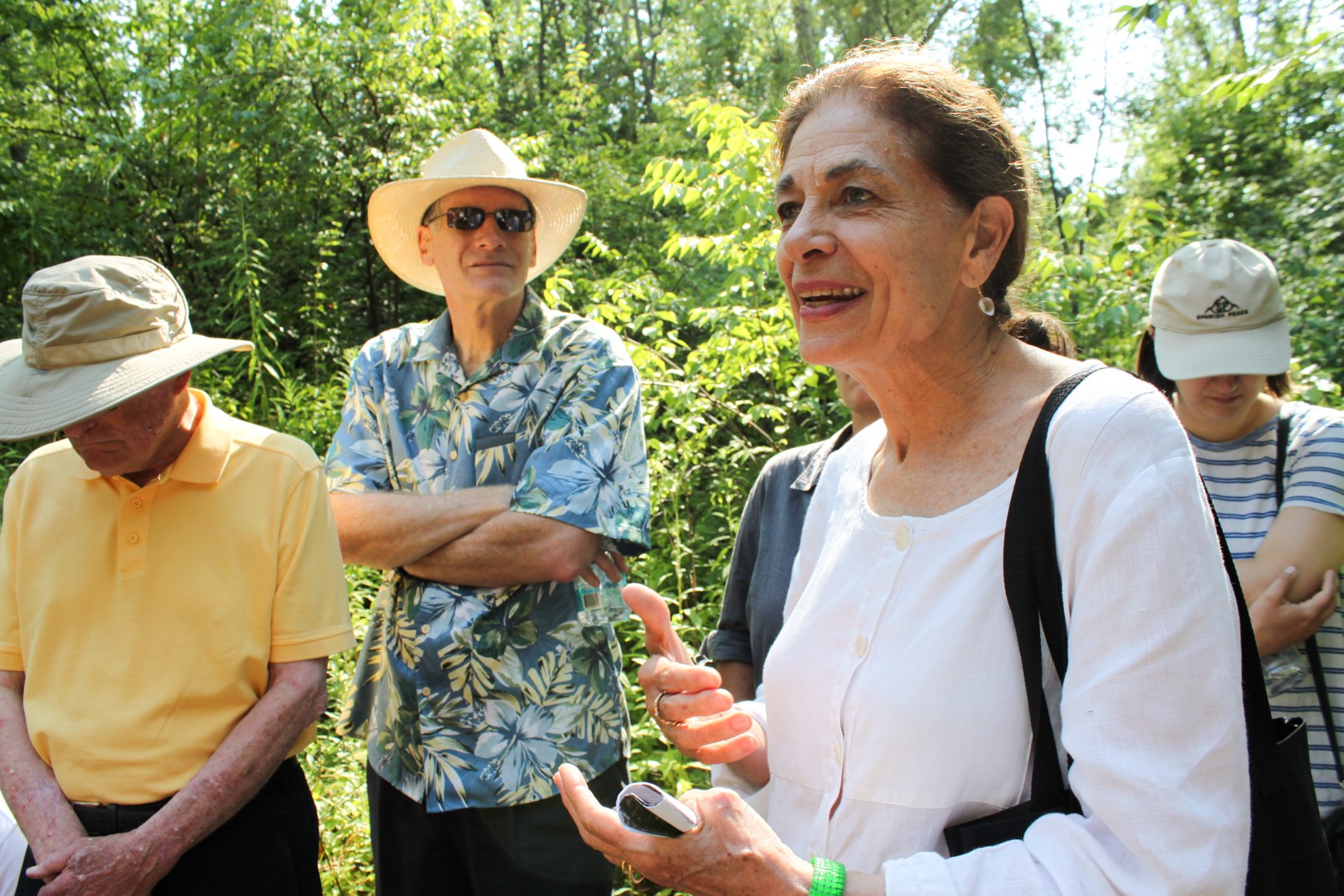 A person shares their thoughts to a group in a forested area.