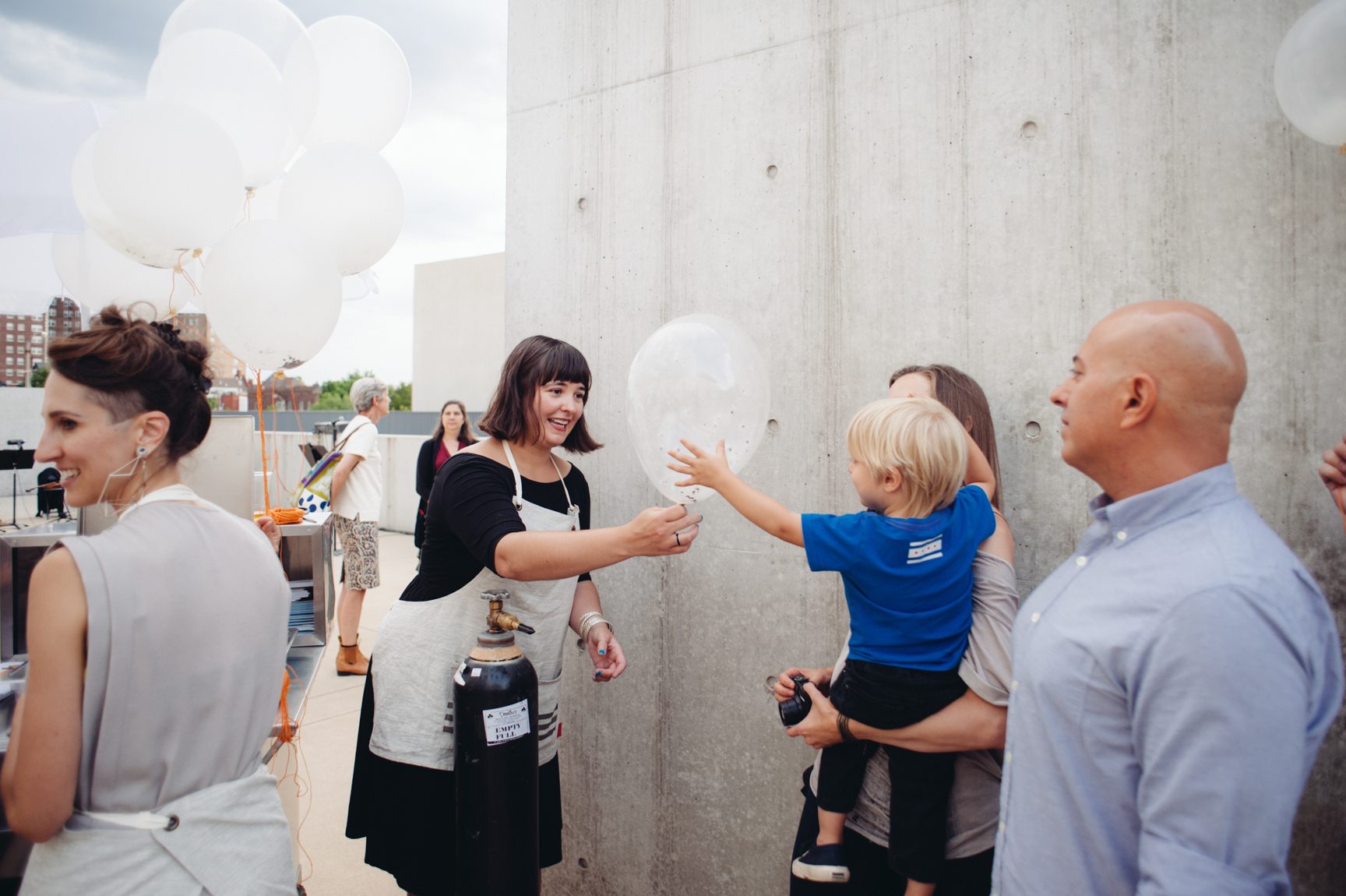 A person hands a child a white balloon during an event in the Courtyard.