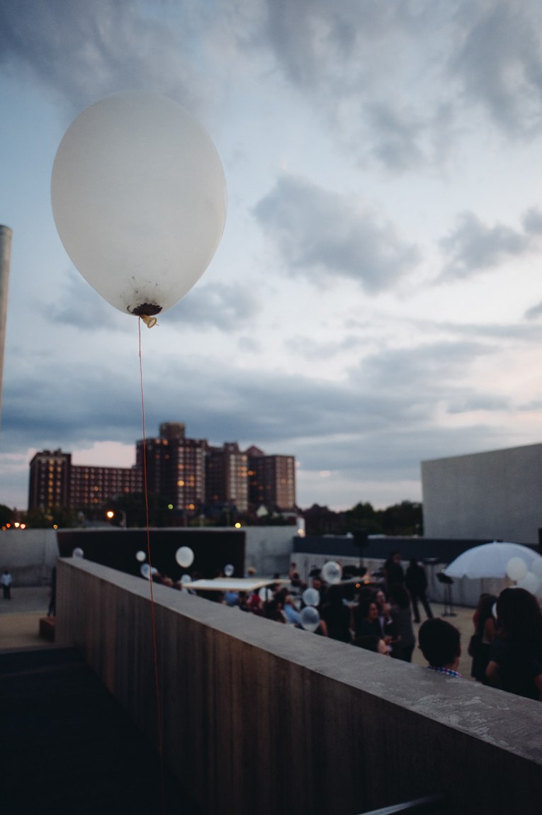 A closeup of a white balloon with a view of a crowd in the Courtyard.