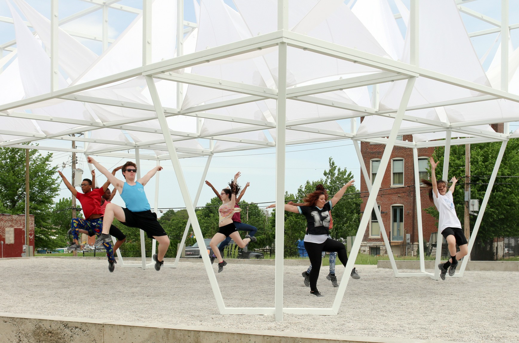 A group of dancers perform together beneath the Lots installation.