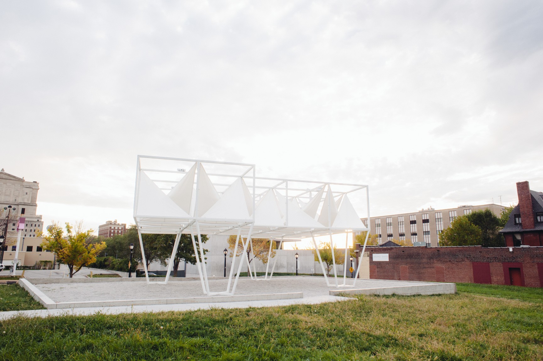 A clear view of the Lots installation, a geometric white sculpture with white triangular fabric pieces attached tautly to the structure's overhead beams.