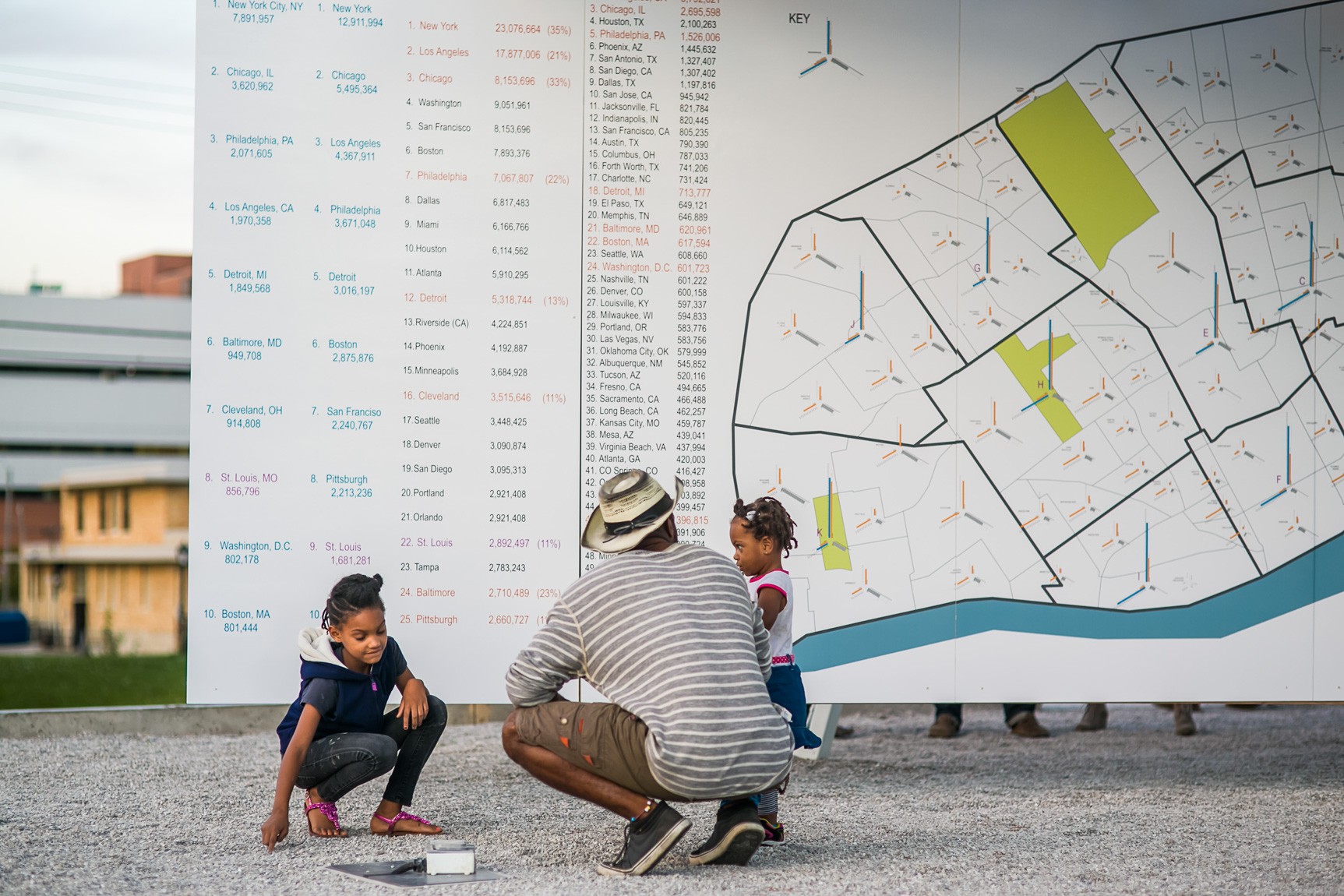 A visitor and their two children crouch gather before a wall of diagrams.