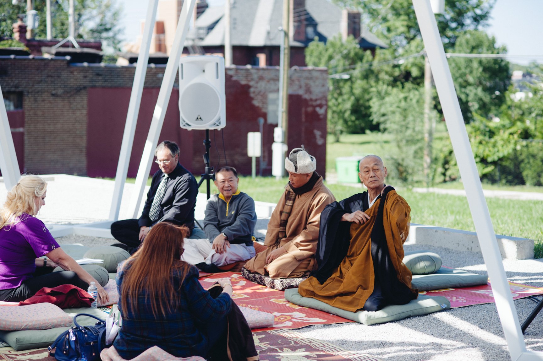Buddhist experts lead an audience in meditation outdoors beneath the Lots installation.