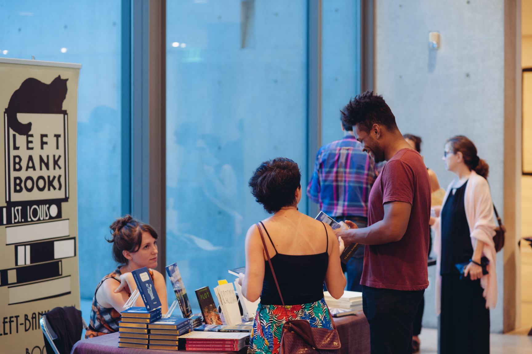 Visitors stop to look at books from a vendor table for Left Bank Books in front of the Water Court windows.