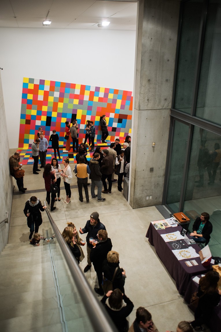 A view from the Mezzanine of event goers socializing in the Main Gallery and by the Water Court windows.