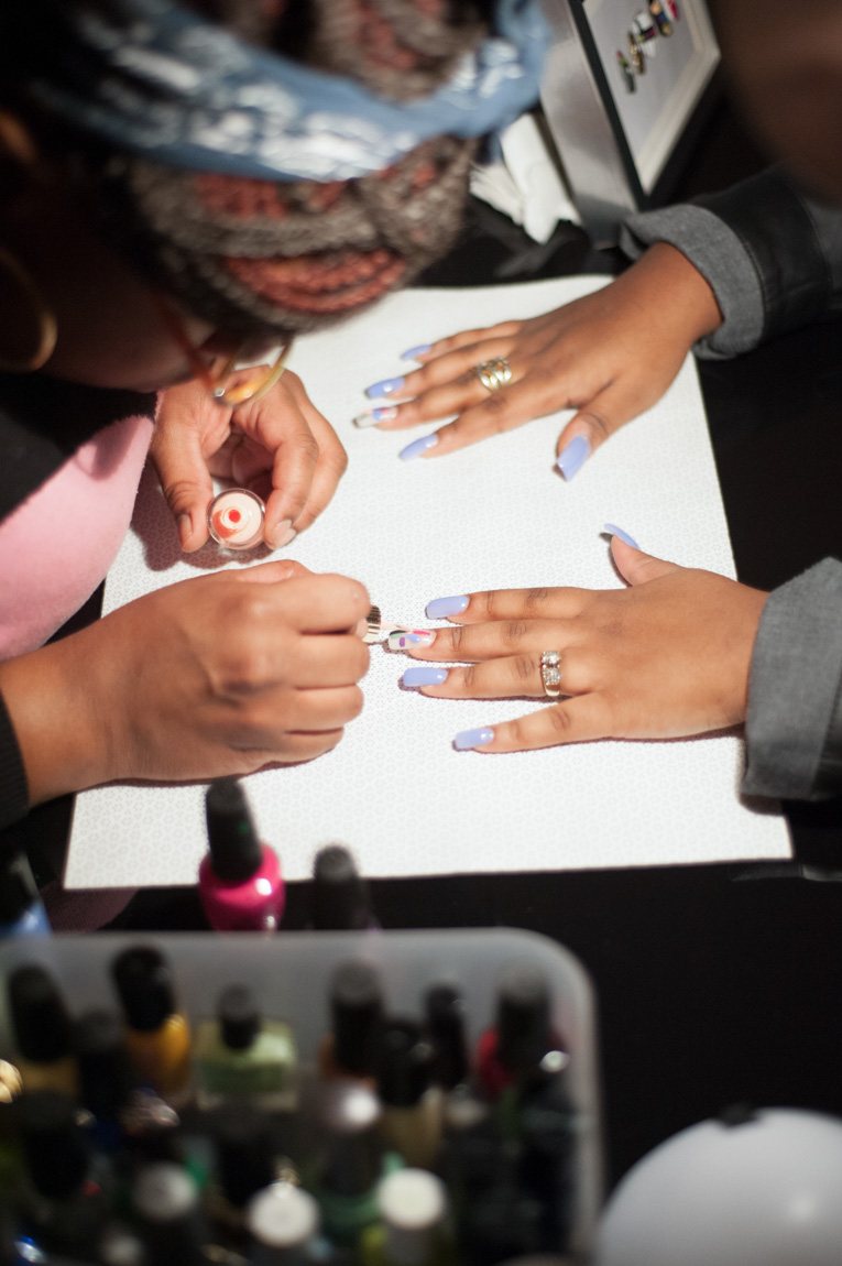 A closeup of a nail artist creating a design on a visitor's nails.
