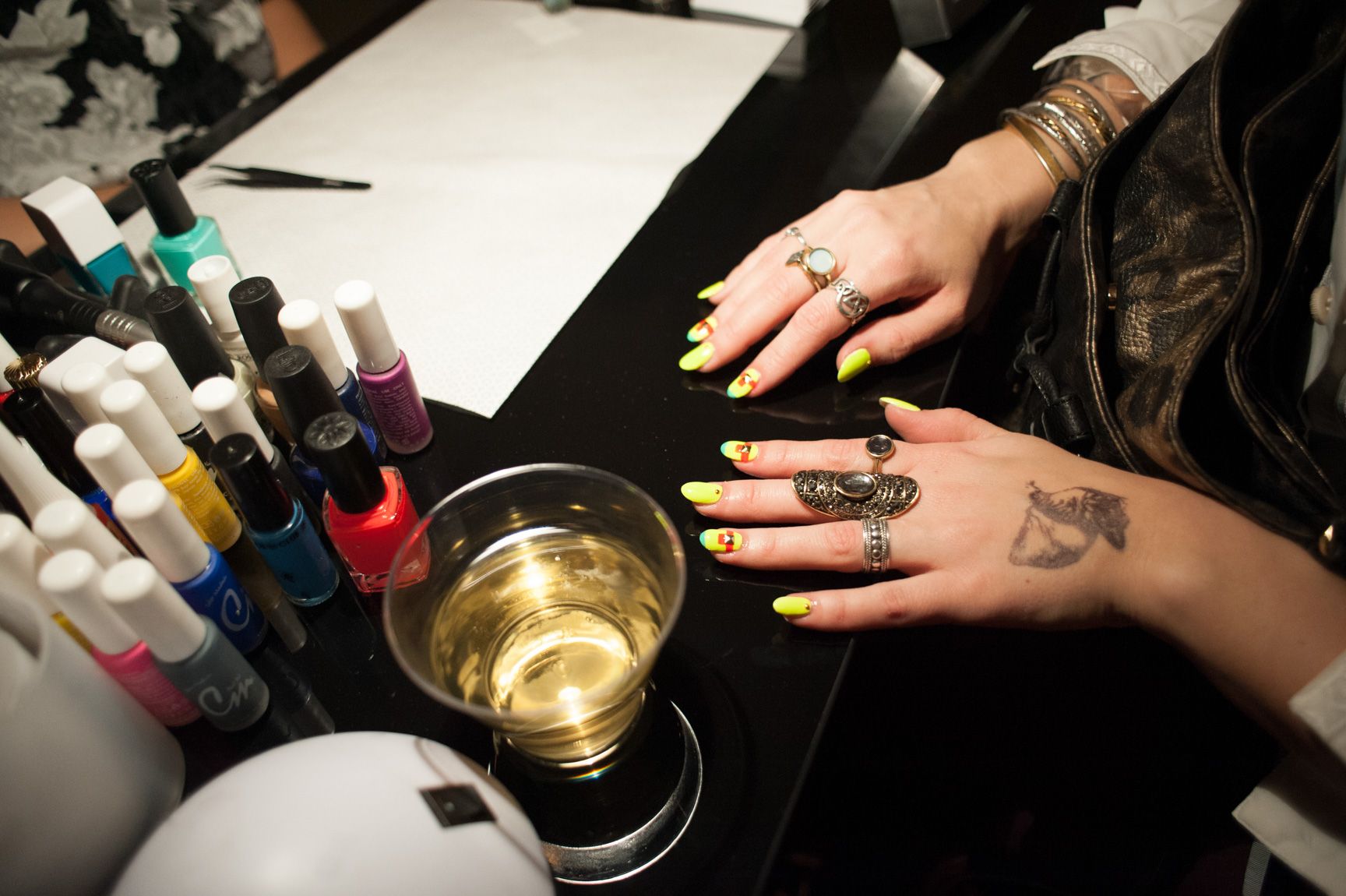 A closeup of a visitor's nails on a table with bottles of nail polish.