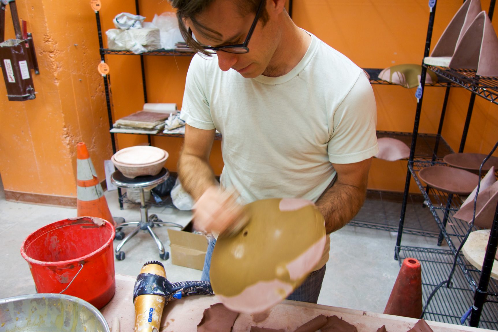 Chris Kallmyer in his studio, glazing a clay instrument.