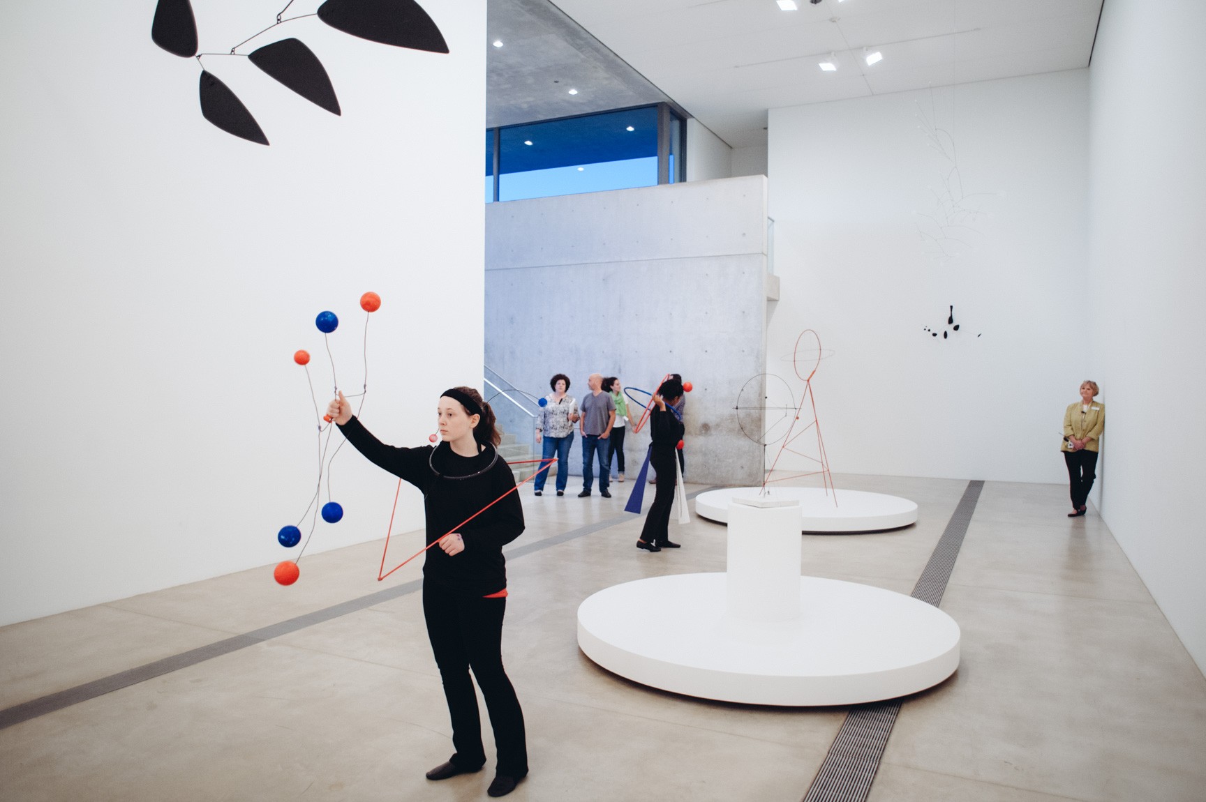 Students perform for a small audience in the Main Gallery, holding and wearing geometric shapes inspired by Calder's sculptures.