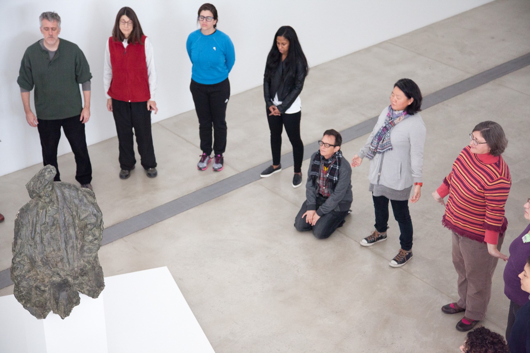 Haruko Tanaka and Asher Hartman lead an exercise workshop with attendants in the Main Gallery, standing and kneeling around Rosso's sculpture of Henri Rouart.