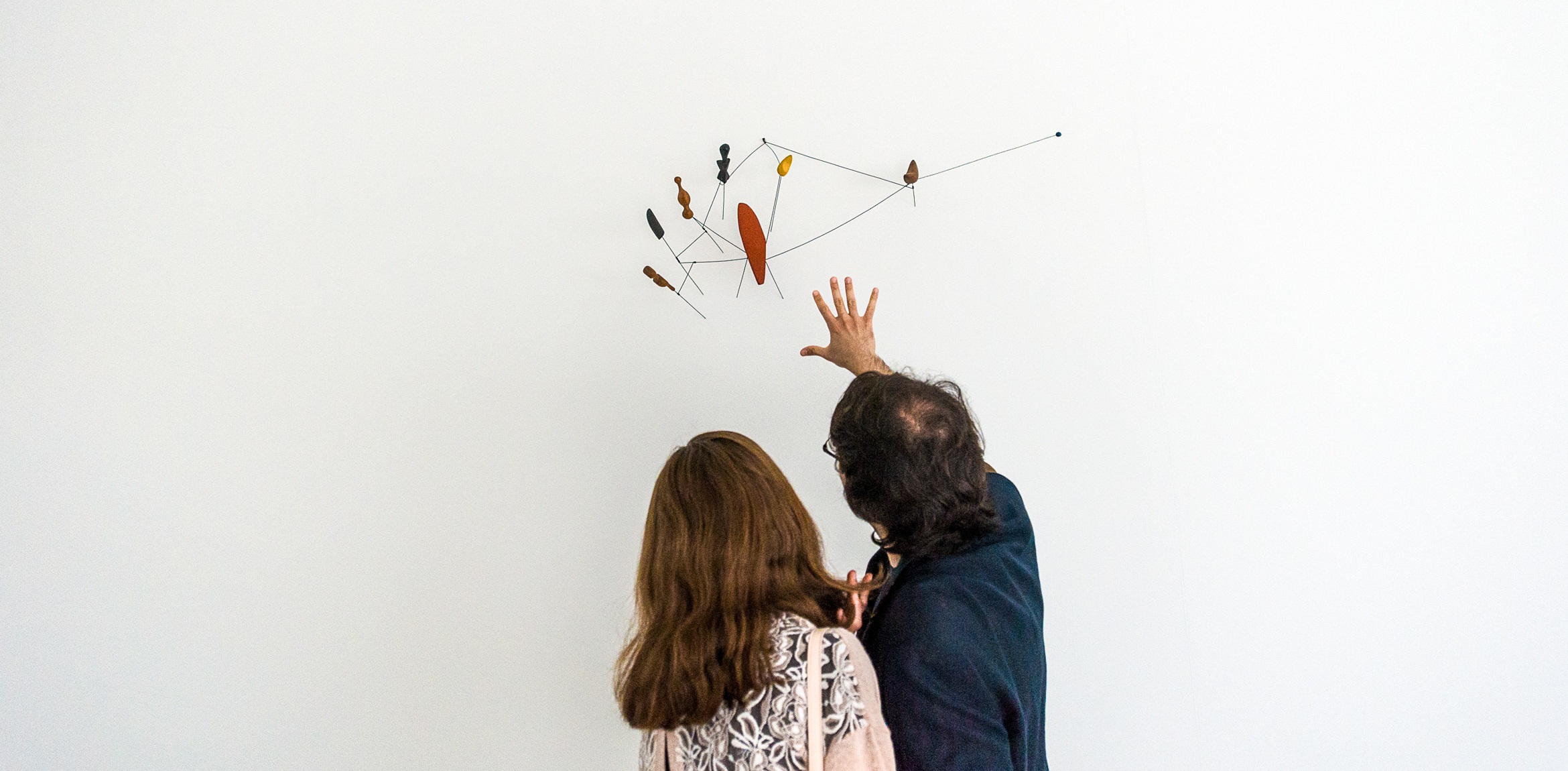 Two guests admiring a Calder mobile.