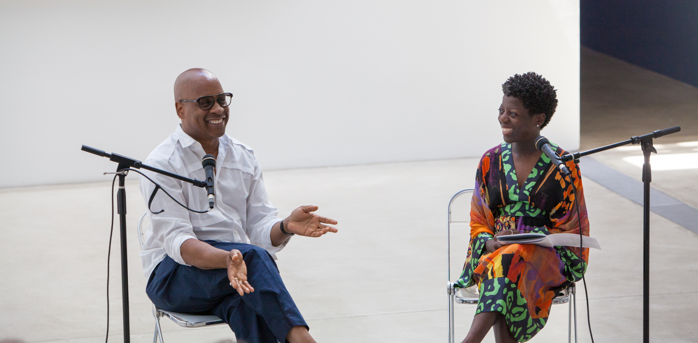 Glenn Ligon and Thelma Golden converse in front of microphones in the Lower Main Gallery.