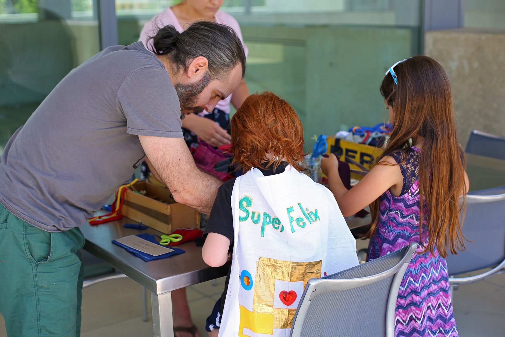 A parent and their children participating in a workshop on the Mezzanine patio.
